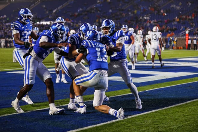 Duke quarterback Riley Leonard, on a knee, is congratulated by teammates after a touchdown against Virginia. 