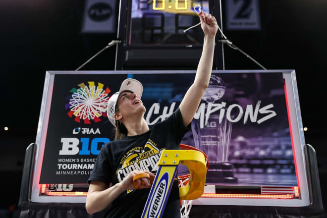 Caitlin Clark raises a piece of the net as she celebrates Iowa's Big Ten Tournament championship Sunday.