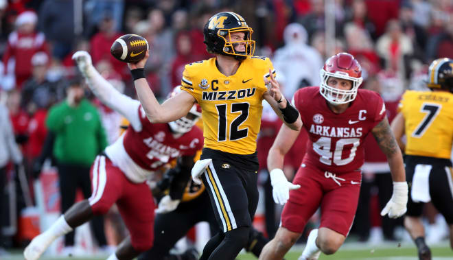 Missouri QB Brady Cook evades the Arkansas pass rush and looks to throw during Friday's win over the Razorbacks in Fayetteville.