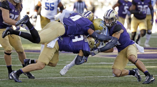 UCLA's Chris Pabico, second from right, is brought down by Washington's Austin Joyner (4), Elijah Molden (3) and Taylor Rapp in the second half of an NCAA college football game Saturday, Oct. 28, 2017, in Seattle. (AP Photo/Elaine Thompson)