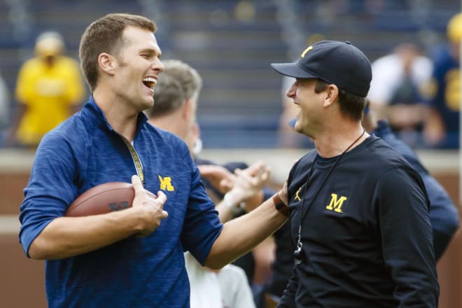 Two Michigan Wolverines football greats, Tom Brady and Jim Harbaugh, share a laugh before a game