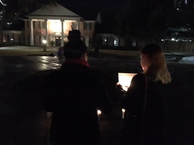 Two members of the group that attended Monday night's vigil read a sheet of paper with the night's objectives illuminated by their candles.