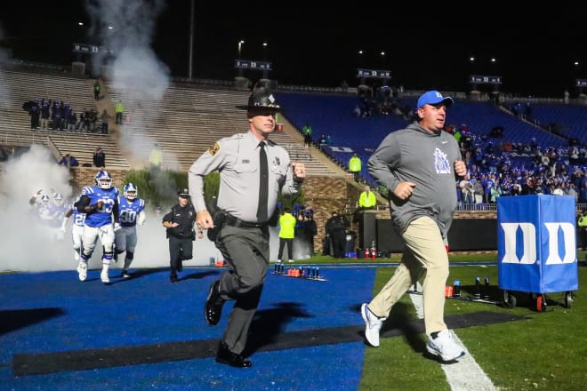 Duke coach Mike Elko, right, takes the field in front of his team before a game this past season. 