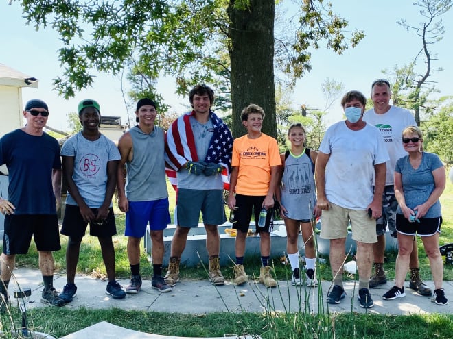 Class of 2022 OL Carson Hinzman, center with the American flag, helped clean up in the Cedar Rapids area on Sunday.