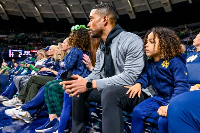 Notre Dame head football coach and two of his kids take in Notre Dame's overtime victory on Thursday night.
