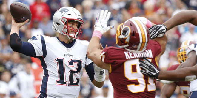  New England Patriots quarterback Tom Brady (12) passes the ball as Washington Redskins outside linebacker Ryan Kerrigan (91) chases in the second quarter at FedExField.