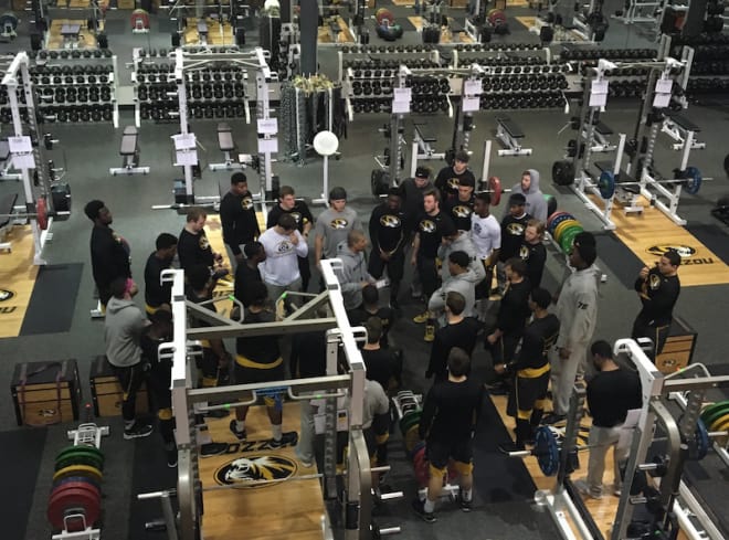 Mizzou players gather around Rohrk Cutchlow in the weight room