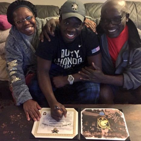CB Michael Mbony surrounded by his parents as he adds his John Hancock.