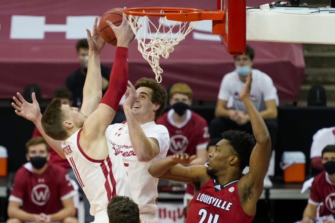 Wisconsin's Micah Potter (11) and Nate Reuvers grab a defensive rebound against Louisville's Jae'Lyn Withers in December.