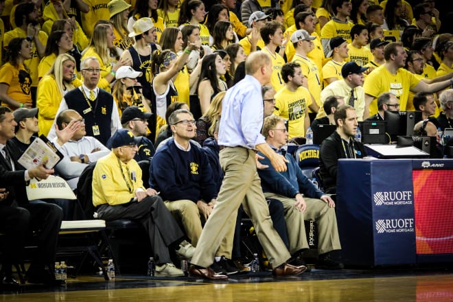 Beilein works while Harbaugh and booster Al Glick look on.