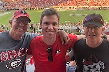 Father and son, Tyler (center) and Chris Redlitz (right), pose with friend Jack Cochran (left) during the 2018 Georgia-Tennessee game.