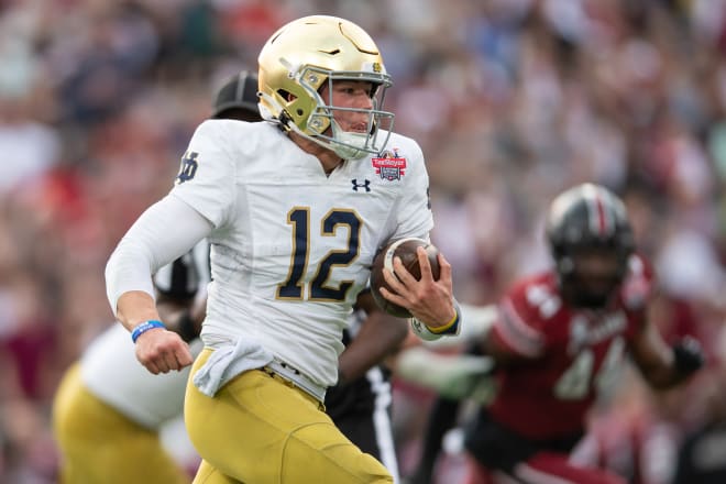 Notre Dame sophomore quarterback Tyler Buchner (12) carries the ball against South Carolina in the Gator Bowl.