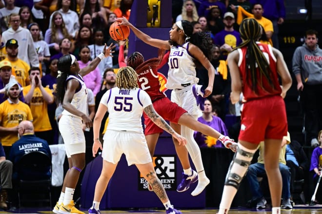 LSU forward Angel Reese blocks an Arknasas shot with her right hand while she holds her shoe in her left hand after it fell off a few seconds before in the Lady Tigers' SEC win over the Razorbacks on Thursday night in the PMAC.