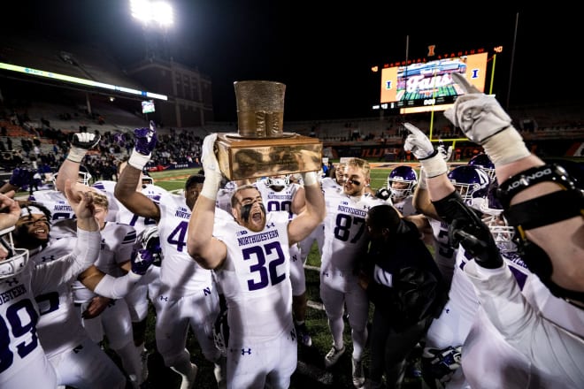 Bryce Gallagher raises the Land of Lincoln Trophy to celebrate Northwestern's win over Illinois.