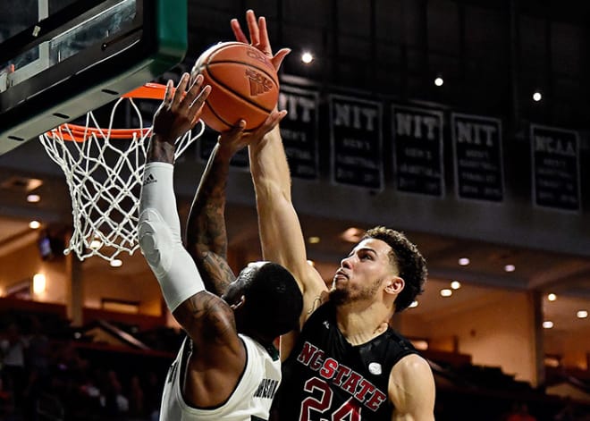 NC State redshirt sophomore wing Devon Daniels goes up for a big block against Miami senior guard Zach Johnson during the Wolfpack's 87-82 win Thursday in Coral Gables, Fla.