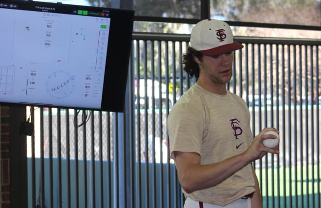 Cam Leiter examines his grip while analytics from the prior pitch appears on a screen behind him.