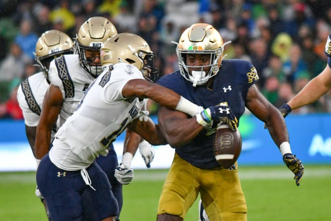 Navy's Rayuan Lane III (18) knocks the ball away from Notre Dame running back Audric Estimé (7) during ND's 42-3 victory Saturday in Ireland. 