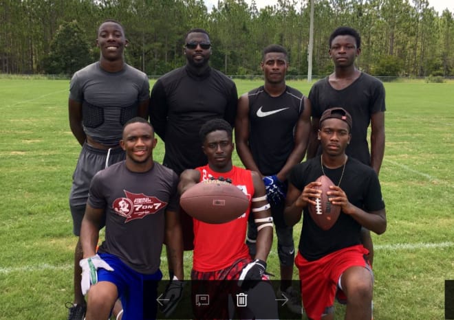 Former FSU defensive back Leroy Smith (second from left, back row) poses with six of his new players during a break in the action at a football camp in Tallahassee last weekend.