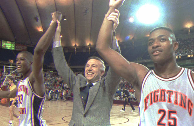 Illinois head coach Lou Henson walks from the court hand-in-hand with players Nick Anderson, left, and Kenny Battle following their 83-69 victory over Louisville in the NCAA tournament, March 25, 1989, in the Metrodome in Minneapolis.