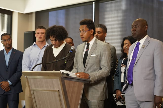 Lloyd Yates, at podium, speaks to the media on July 19 about hazing within the Northwestern program.