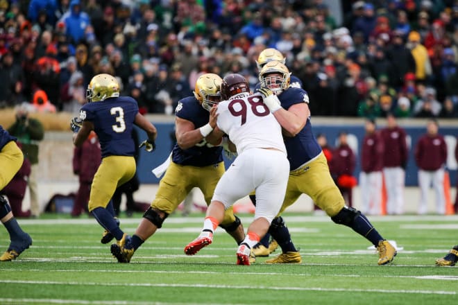 Sam Mustipher (left) and Quenton Nelson block a Virginia Tech defender.