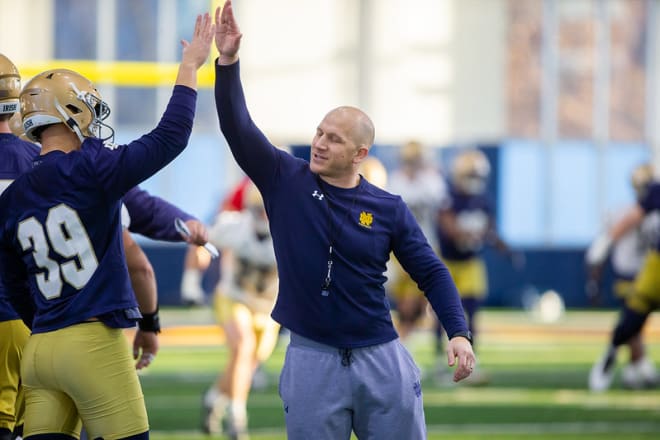 Notre Dame defensive coordinator and linebackers coach Clark Lea high-fiving a player at practice