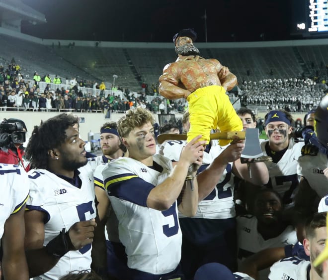 Michigan quarterback J.J. McCarthy hoists the Paul Bunyan Trophy after the Wolverines' 49-0 win over the Michigan State Spartans at Spartan Stadium in East Lansing on Saturday, Oct. 21, 2023.