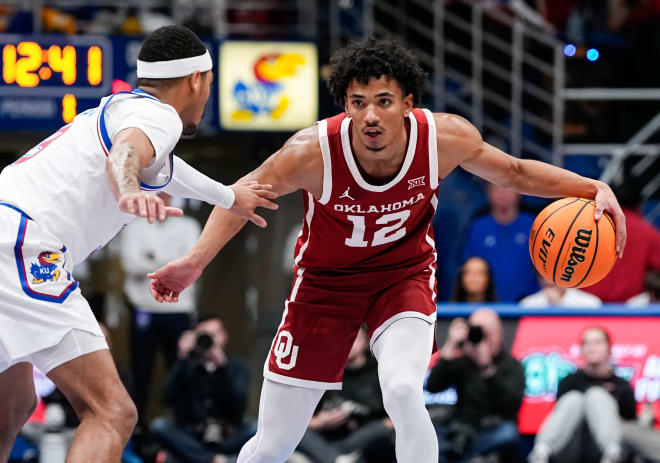 Oklahoma Sooners guard Milos Uzan (12) dribbles the ball against Kansas Jayhawks guard Dajuan Harris Jr. (3) 