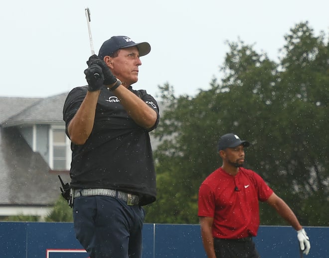 Tiger Woods looks on Sunday as Phil Mickelson hits a shot during their made-for-TV charity golf event.