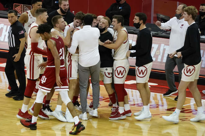 Alando Tucker (white shirt, center) hugs Tyler Wahl after Wahl hit a second straight 3-pointer in double overtime, setting the stage for an 80-73 victory over Indiana.