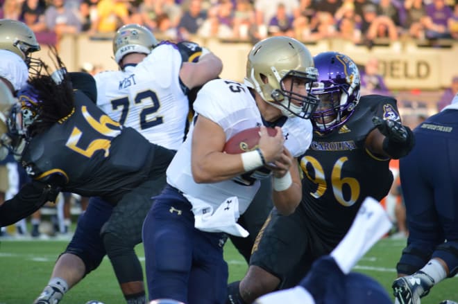 Navy quarterback Will Worth looks for running room around East Carolina's Kiante Anderson. 