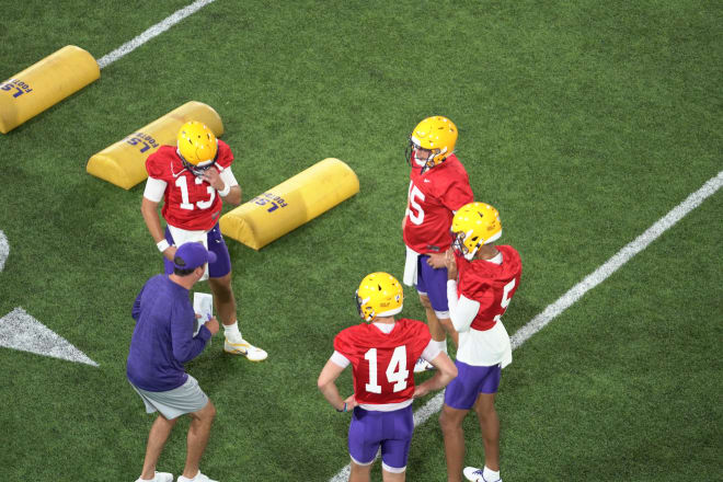 LSU quarterbacks Garrett Nussmeier (13), Myles Brennan (15), Jayden Daniels (5) and Walker Howard (14) listen to Tigers' QB coach Joe Sloan on the opening day of preseason practice Thursday. 