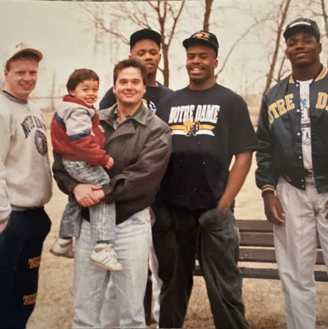 In this 1990 photo shoot, recruiting analyst Tom Lemming holds his son and is surrounded by (from left) Notre Dame recruits Pete Bercich, Brian Hamilton, Oliver Gibson and Bryant Young.