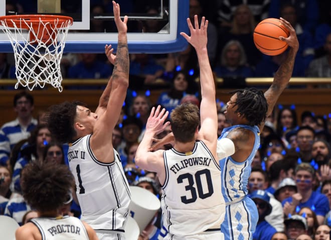 Dereck Lively II, left, and Kyle Filipowski go up to block a dunk attempt of UNC's Caleb Love during Saturday night's game. 