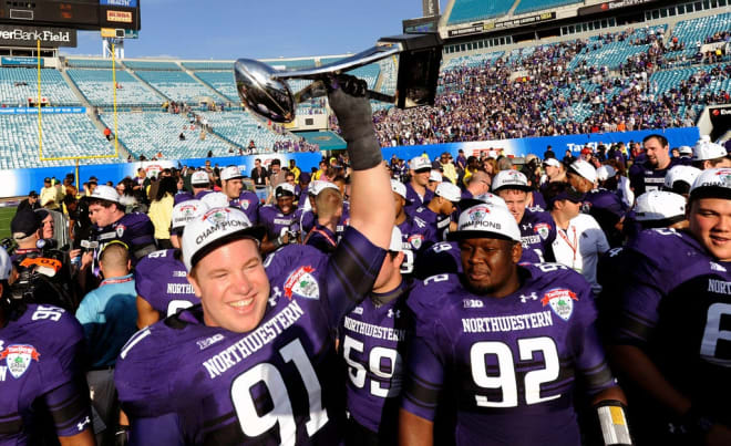 Brian Arnfelt holds up the Gator Bowl trophy.