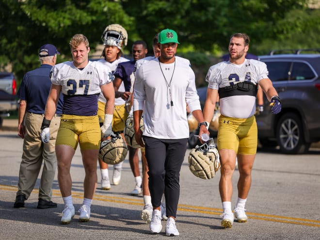 Notre Dame head coach Marcus Freeman, center, walks to the practice field Wednesday before preseason camp gets underway.