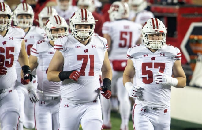 Wisconsin inside linebacker Jack Sanborn (57) and left tackle Cole Van Lanen (71) run on the field during pregame at Michigan in 2020.