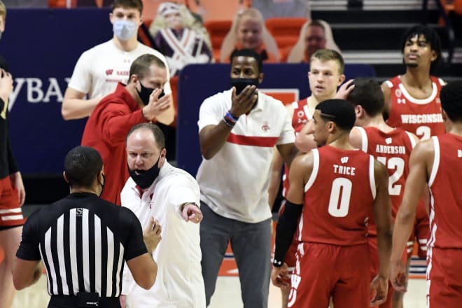 Wisconsin Head Coach Greg Gard, front left, discuss a call with an official during a time out in the second half of an NCAA college basketball game at Illinois