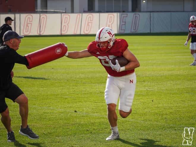 Husker tight end Nate Boerkircher stiff-arms a bag held by his position coach Josh Martin during Tuesday's practice.