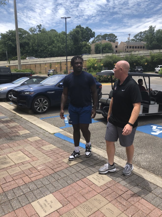 Five-star defensive tackle Tyre West walks toward FSU's Moore Athletics Center with defensive coordinator Adam Fuller.