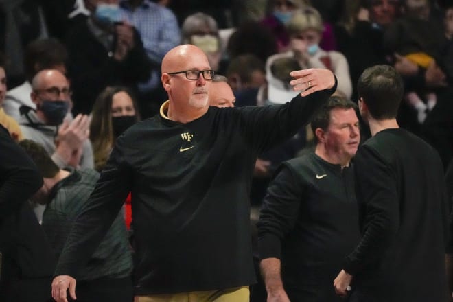 Steve Forbes motions to his team during a game, while his staff goes to work behind him. 