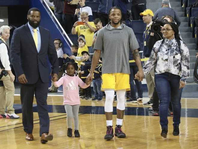 Michigan Wolverines basketball player Zavier Simpson walks out with his family on senior night.