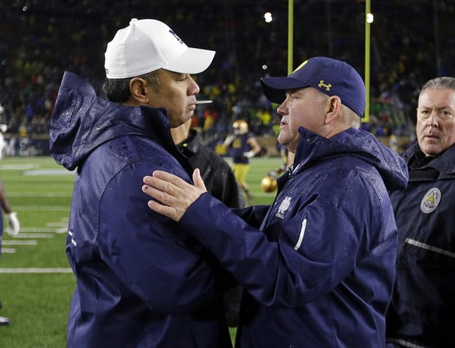 Navy head coach Ken Niumatalolo meeting with Notre Dame head coach Brian Kelly after a game.