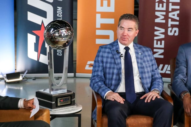 Coach Nick McDevitt is interviewed next to the conference's championship trophy during C-USA media day (Photo Credit @MT_MBB on twitter.com).