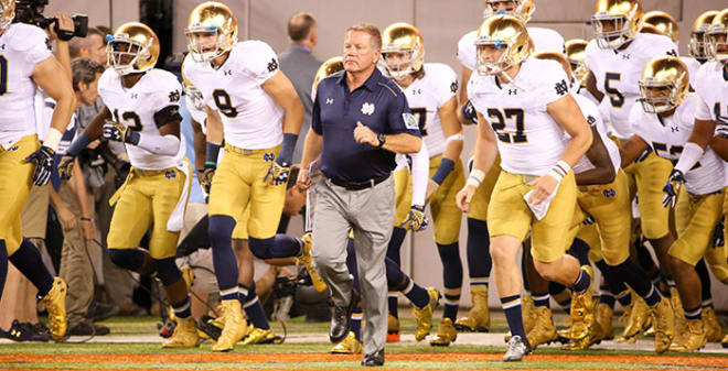 Notre Dame football head coach Brian Kelly leading him team onto the team the field before a game