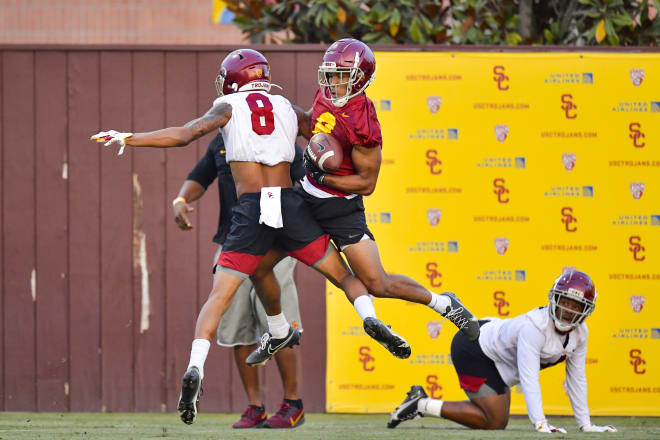 Cornerback Chris Steele (8 white) and wide receiver Amon-Ra St. Brown tangle in the air Friday.