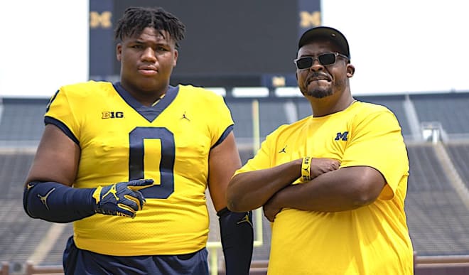 Five-star defensive tackle Walter Nolen holds a Michigan Wolverines football recruiting, Jim Harbaugh.