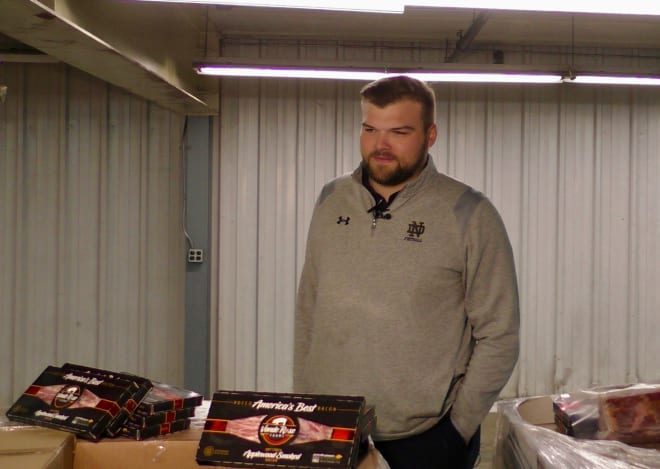 Notre Dame Football Director of Player Development Hunter Bivin standing in front of the pork products from Iowa Gov. Kim Reynolds.