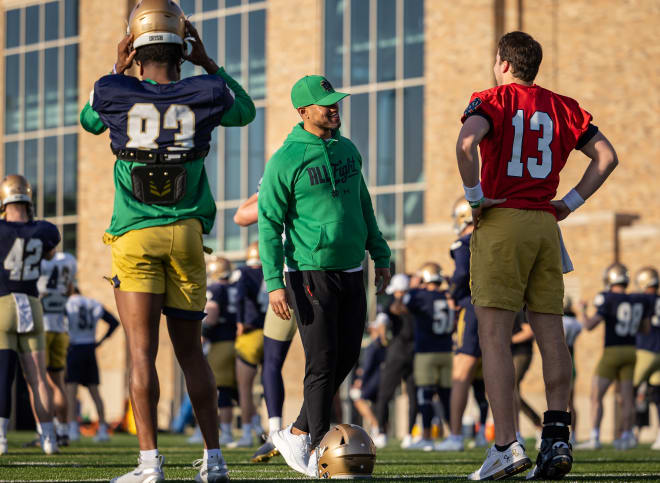 Notre Dame coach Marcus Freeman (center) chats with QB Riley Leonard (13) and wide receiver Jayden Thomas (83) during spring practice warmups.