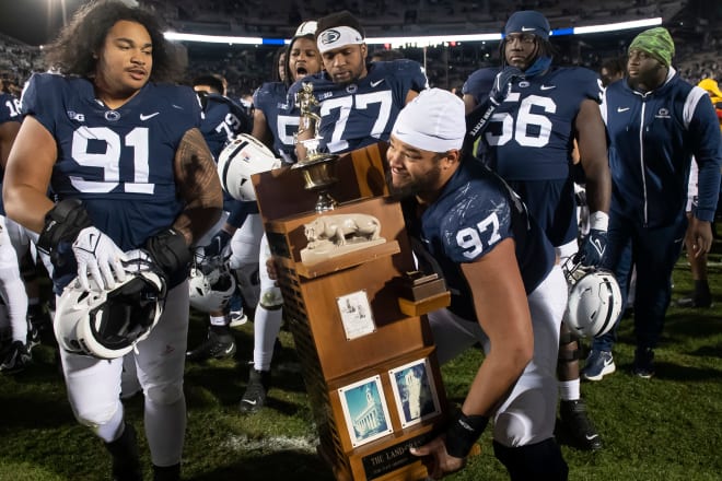 Penn State football players celebrate with the Land-Grant Trophy after defeating Michigan State in 2022.